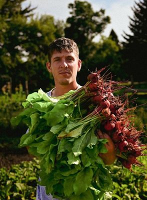 Brian Berglund holding an armful of freshly pulled beets and greens in the Western Variety Farm garden